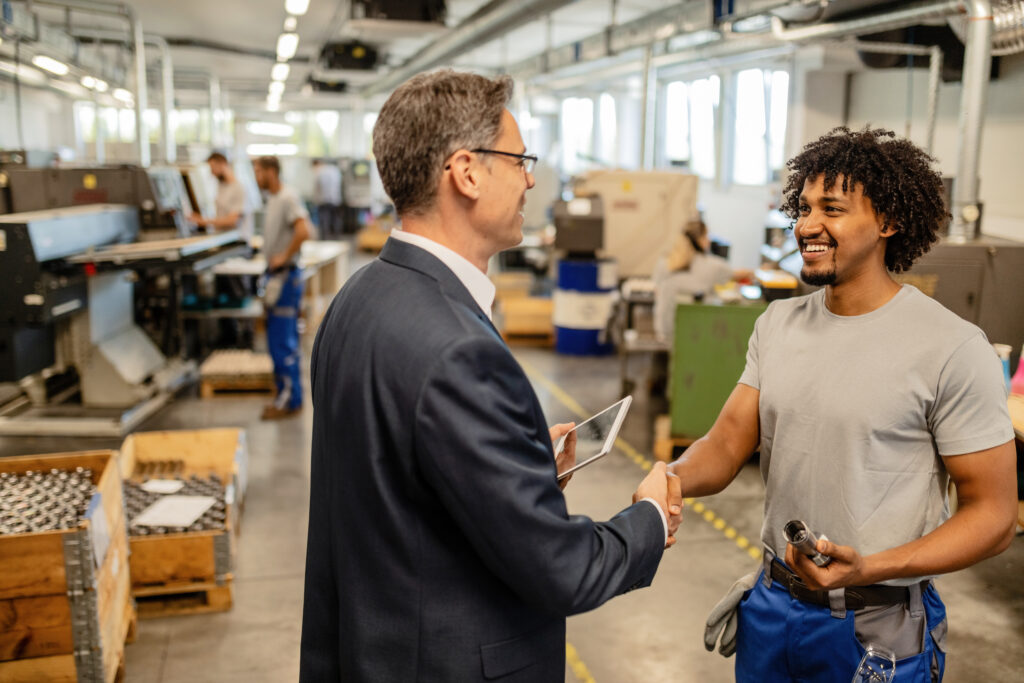 happy african american worker greeting his manager in industrial building.